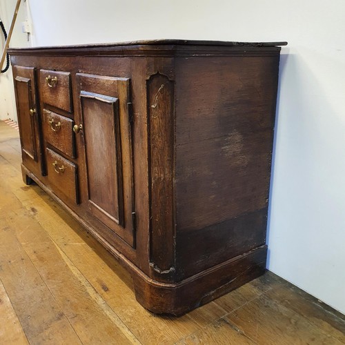 643 - An oak dresser base, having three drawers, flanked by two cupboard doors, 165 cm wide