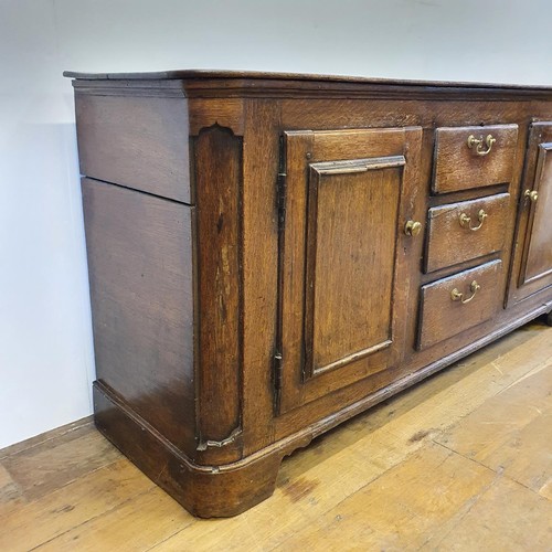 643 - An oak dresser base, having three drawers, flanked by two cupboard doors, 165 cm wide