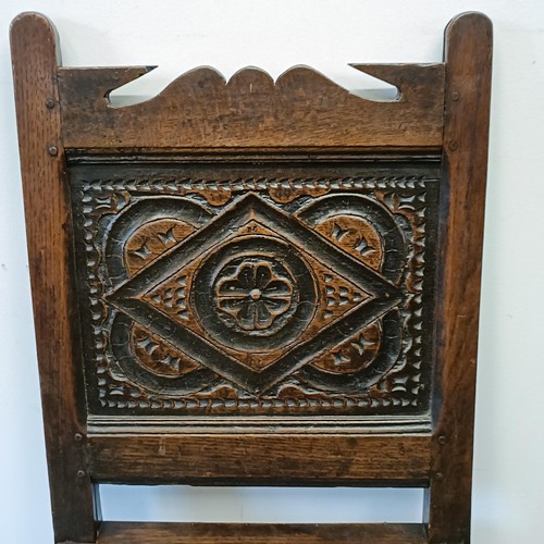 555 - A 17th century single chair, with a carved panel back and seat, on turned legs