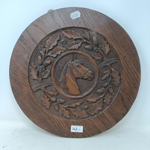 242 - A carved oak roundel, decorated horse, surrounded by oak leaves, 42 cm diameter, and a mahogany shel... 