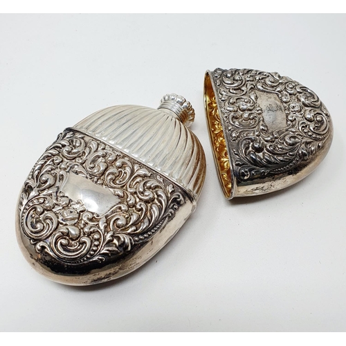 661 - A Sterling silver flask and cup, of oval form, embossed scrolling foliage, 2.6 ozt, 12 cm high