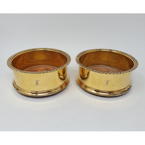 664 - A pair of George III style silver gilt wine coasters, initialled, London 1985, 11 cm diameter (2)