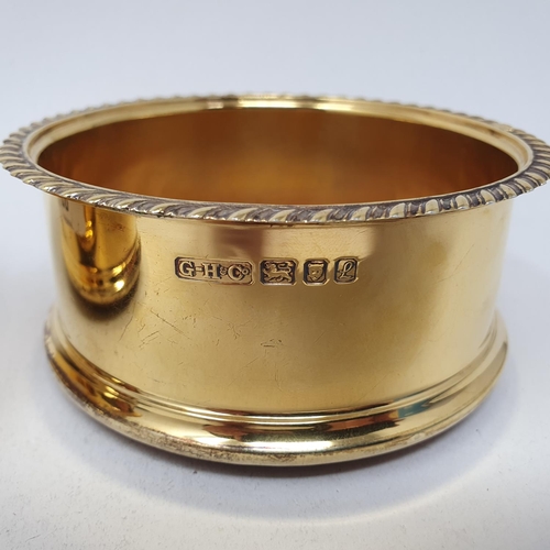 664 - A pair of George III style silver gilt wine coasters, initialled, London 1985, 11 cm diameter (2)