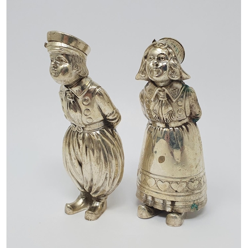 606 - A pair of Continental silver coloured metal condiments, in the form of a boy and a girl, each with t... 