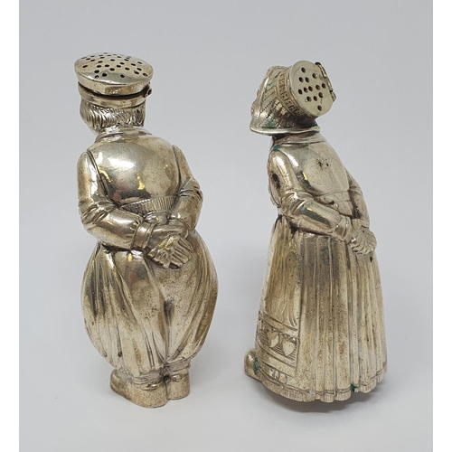 606 - A pair of Continental silver coloured metal condiments, in the form of a boy and a girl, each with t... 