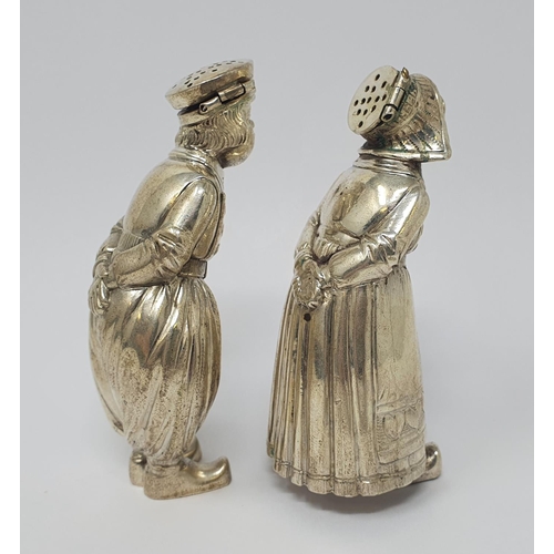 606 - A pair of Continental silver coloured metal condiments, in the form of a boy and a girl, each with t... 