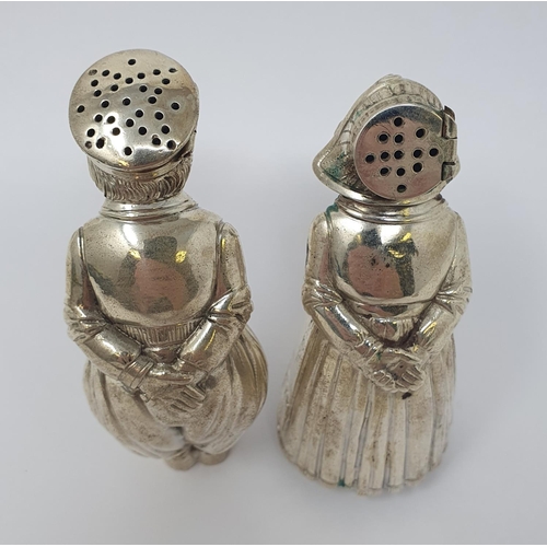 606 - A pair of Continental silver coloured metal condiments, in the form of a boy and a girl, each with t... 