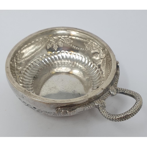 612 - A silver coloured metal wine taster, with a serpent ring handle, 11.5 cm wide