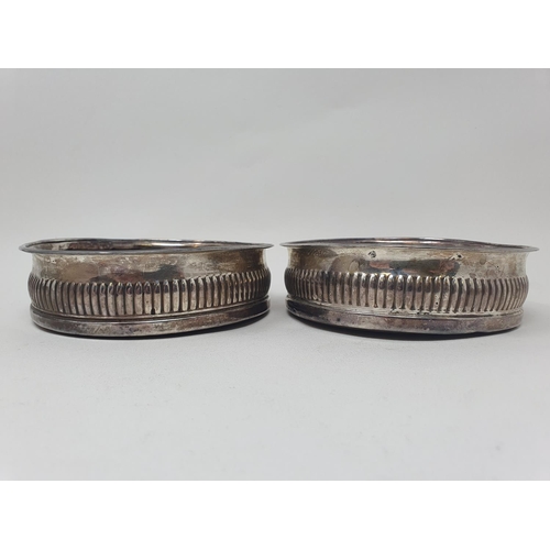 577 - A pair of early 19th century silver wine coasters, with reeded lower bodies, marks indistinct (2)