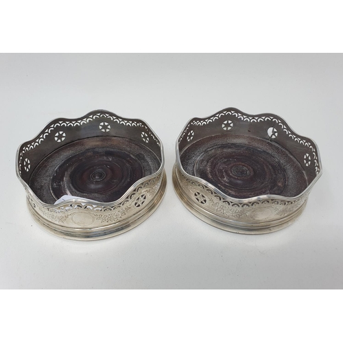 593 - A pair of early 19th century silver coasters, with a wavy rim, with pierced and engraved decoration,... 