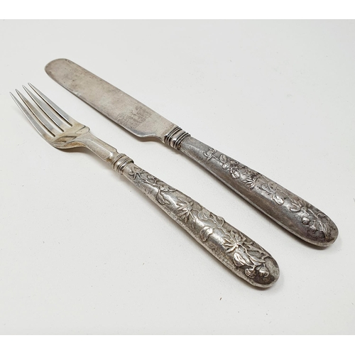 646 - A Chinese silver coloured metal christening knife and fork set, decorated flowers and foliage, the k... 