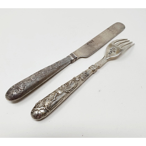 646 - A Chinese silver coloured metal christening knife and fork set, decorated flowers and foliage, the k... 