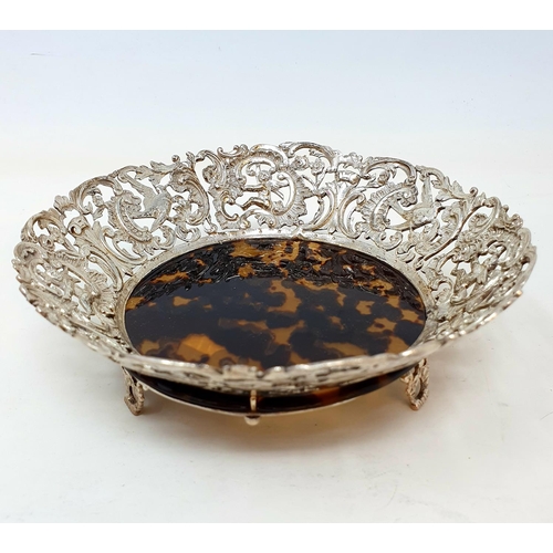 580 - A late Victorian silver and tortoiseshell dish, the borders pierced and decorated with cherubs, bird... 