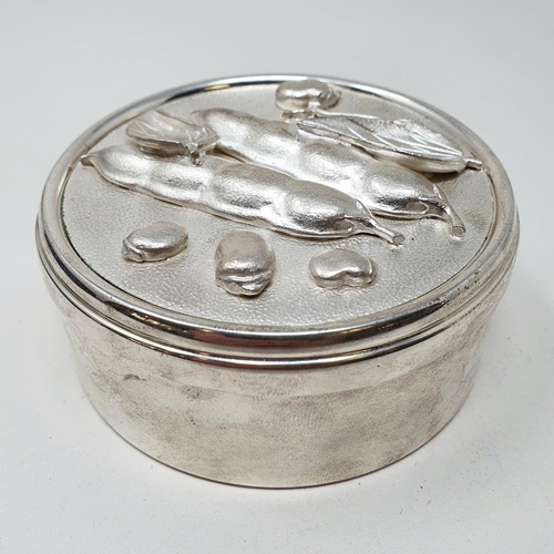 695 - A modern silver box and cover, of cylindrical form, the cover decorated peas in high relief, Asprey'... 