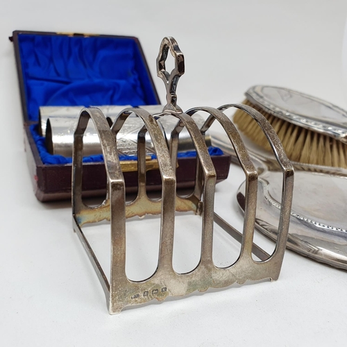 627 - A silver toast rack, set of aesthetic style napkin rings, a silver backed mirror and brush, various ... 