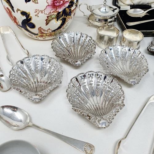 705 - A set of four George V silver pierced bowls, in the form of shells, a two piece cruet, two napkin ri... 