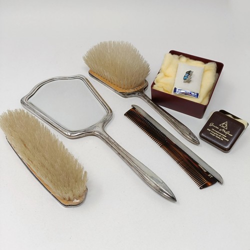 710 - A modern silver backed mirror, two matching brushes, and a comb (4)