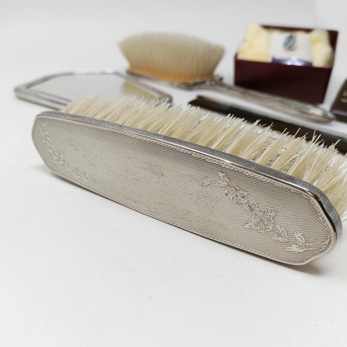 710 - A modern silver backed mirror, two matching brushes, and a comb (4)