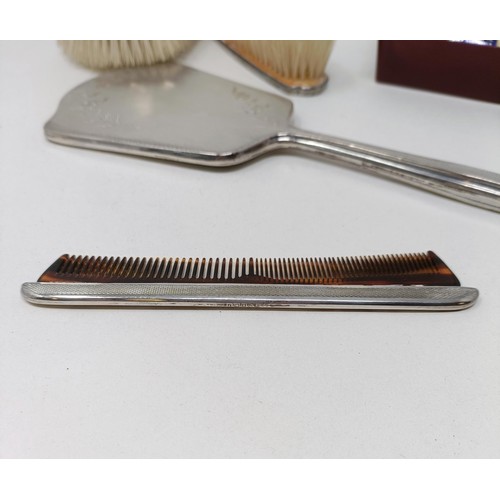 710 - A modern silver backed mirror, two matching brushes, and a comb (4)