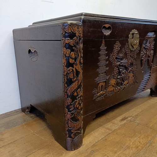 1319 - A carved camphorwood chest, decorated a landscape with figures, 100 cm wide