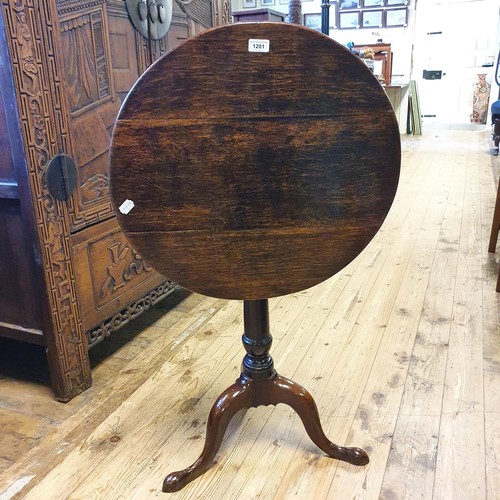 1201 - A 19th century oak tilt top table, on a column support to a tripod base, 54 cm diameter