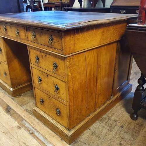 1202 - An oak pedestal desk, of nine drawer configuration, with cupboards to the sides, 122 cm wide