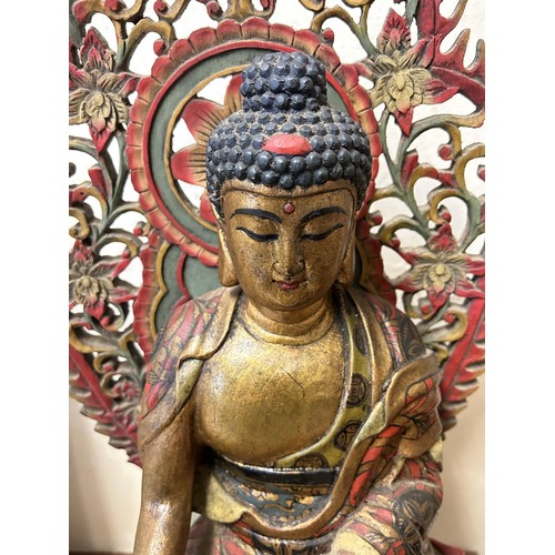 1010 - A painted and carved wooden Buddha on a stand, 50 cm high