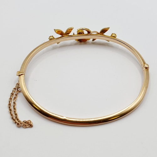 79 - An early 20th century yellow metal and seed pearl bangle, decorated leaves and a crescent, 7.4 g