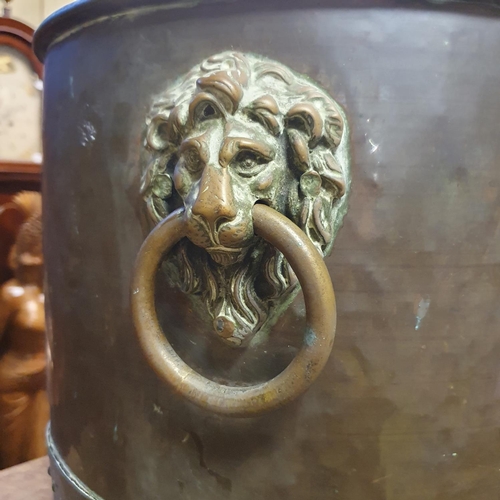 865 - A brass coal bin, with lion's head ring handles, on paw feet, 39 cm diameter