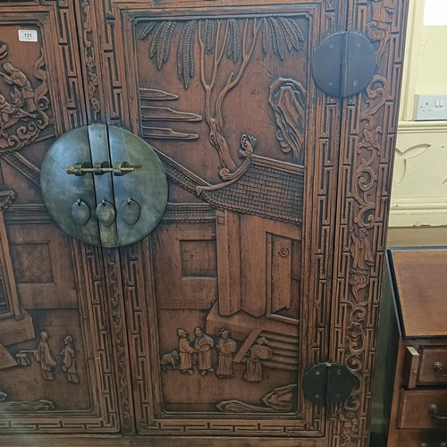 863 - A Chinese two door wardrobe, carved a town scene with figures, 170 cm high x 131 cm wide