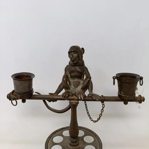 663 - A bronze two branch candelabrum, the finial in the form of a monkey, 29 cm high