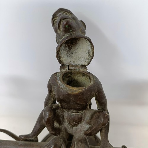 663 - A bronze two branch candelabrum, the finial in the form of a monkey, 29 cm high