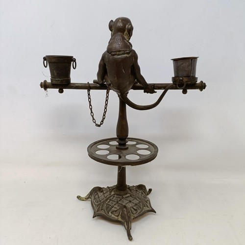 663 - A bronze two branch candelabrum, the finial in the form of a monkey, 29 cm high