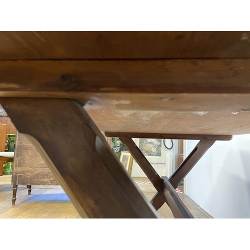 910 - A tavern table, the pine X framed support united by a stretcher, 150 cm wide