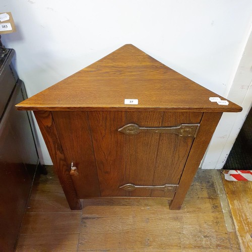 37 - An Arts and Crafts smokers oak corner cabinet, having a pair of wrought iron hinges, 53 cm high