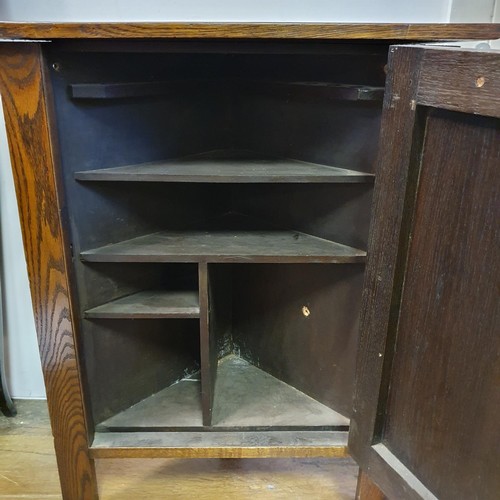 37 - An Arts and Crafts smokers oak corner cabinet, having a pair of wrought iron hinges, 53 cm high