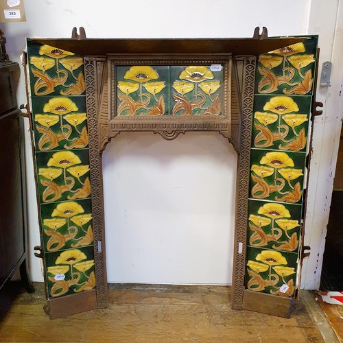 40 - An Art Nouveau style cast iron fire surround, inset with floral tiles, 83 cm high x 73 cm wide