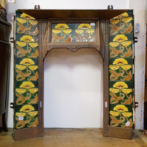 40 - An Art Nouveau style cast iron fire surround, inset with floral tiles, 83 cm high x 73 cm wide