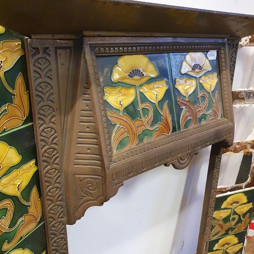 40 - An Art Nouveau style cast iron fire surround, inset with floral tiles, 83 cm high x 73 cm wide