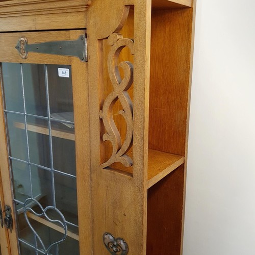 145 - An Arts & Crafts 'Grosvenor' oak bookcase, with two leaded glazed doors, decorated heart shaped moti... 