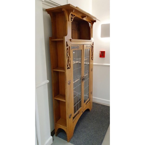 145 - An Arts & Crafts 'Grosvenor' oak bookcase, with two leaded glazed doors, decorated heart shaped moti... 