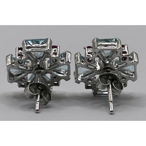 44 - A pair of silver coloured metal, topaz and ruby earrings...