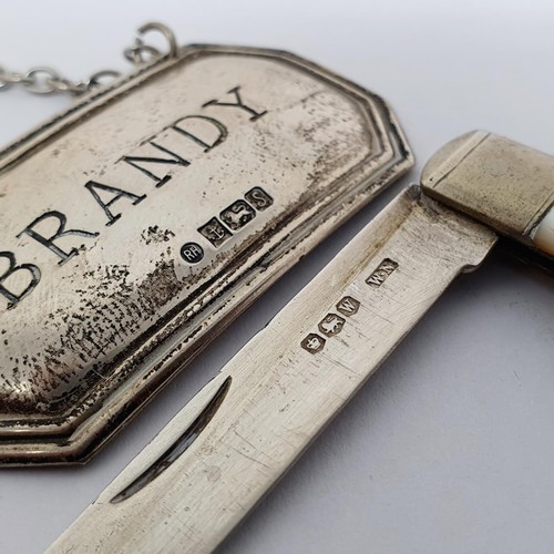 285 - A Victorian silver caddy spoon, a fruit knife, a Brandy label, a pickle fork, and a brooch in the fo... 