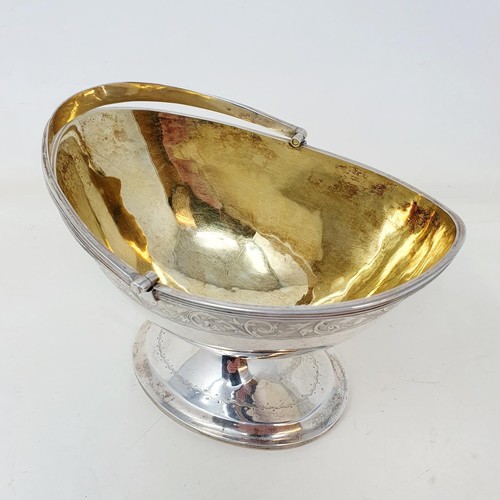 373 - A Victorian silver sugar basket, with a swing handle and engraved decoration, on an oval pedestal fo... 