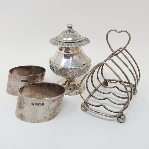 311 - A Indian silver coloured metal pepperette, a four division toast rack, and a set of napkin rings, va... 