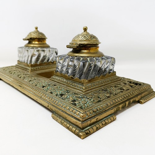 504 - An early 20th century brass inkstand, with a pair of glass inkwells, 36 cm wide