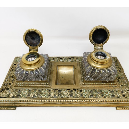 504 - An early 20th century brass inkstand, with a pair of glass inkwells, 36 cm wide