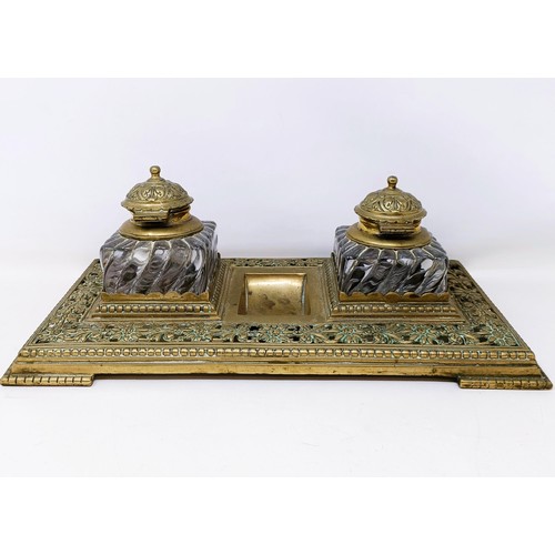 504 - An early 20th century brass inkstand, with a pair of glass inkwells, 36 cm wide