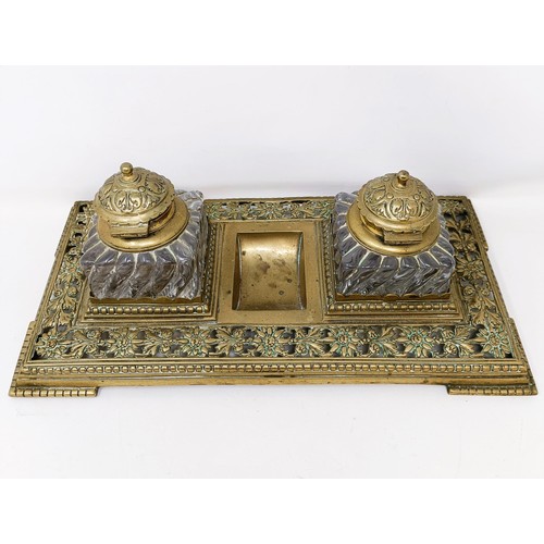 504 - An early 20th century brass inkstand, with a pair of glass inkwells, 36 cm wide