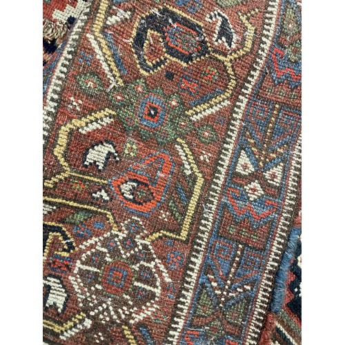 945 - A Persian red ground carpet multiple borders, the centre with three lozenge shaped stepped medallion... 